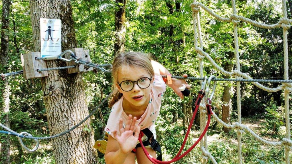 La Fête Continue 5 Fillette souriante sur le parcours accrobranche dans les arbres, colonie d’été à Castelnaudary